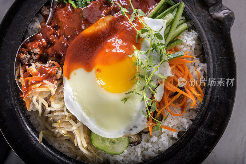 BI Bim Bap，拌菜饭，顶视图与热酱在铸铁锅